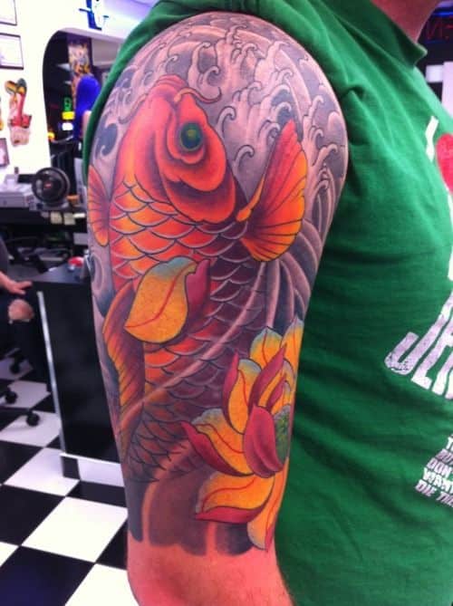 upstream koi fish tattoo on the upper arm of a young man
